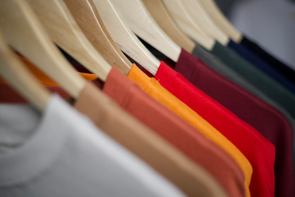 T-shirts unis de différentes couleurs suspendus sur des cintres en bois