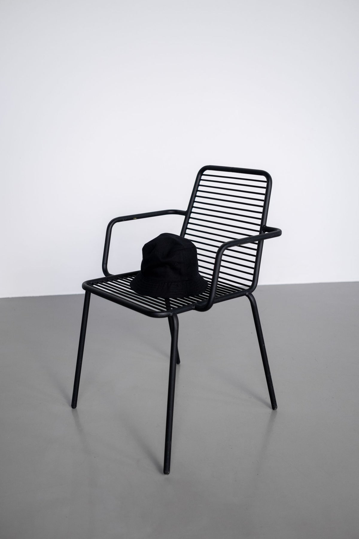 Bob noir posé sur une chaise métallique devant un fond clair